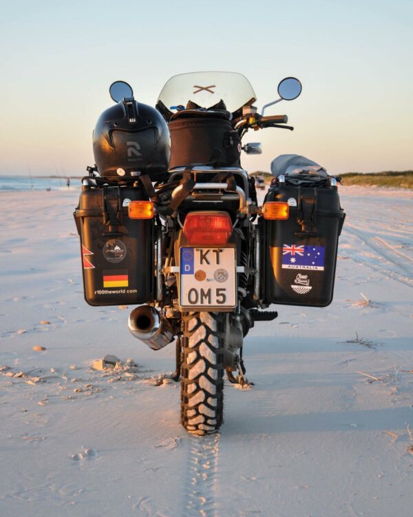 A motorcycle parked on a sandy beach at sunset