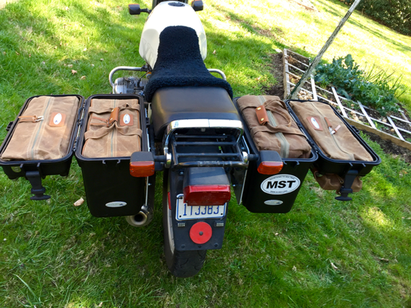 A rear view of a motorcycle with brown canvas bags