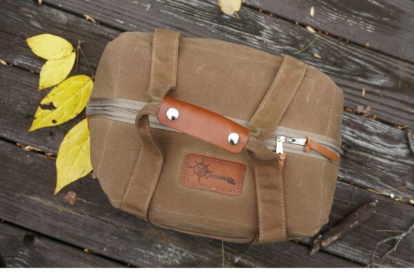 A brown canvas bag with leather accents rests on wooden planks