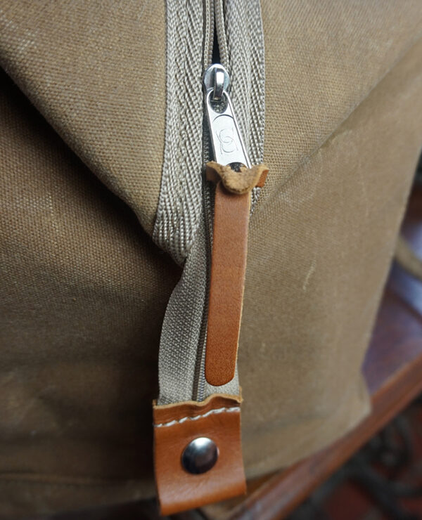 Close-up of a metal zipper on a brown canvas bag
