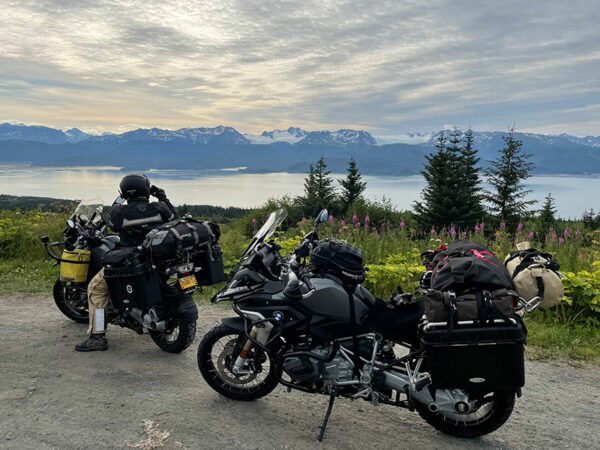 Two fully-loaded motorcycles parked overlooking a scenic mountain view