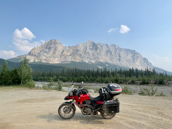 A red motorcycle parked on a dirt road under a clear blue sky.