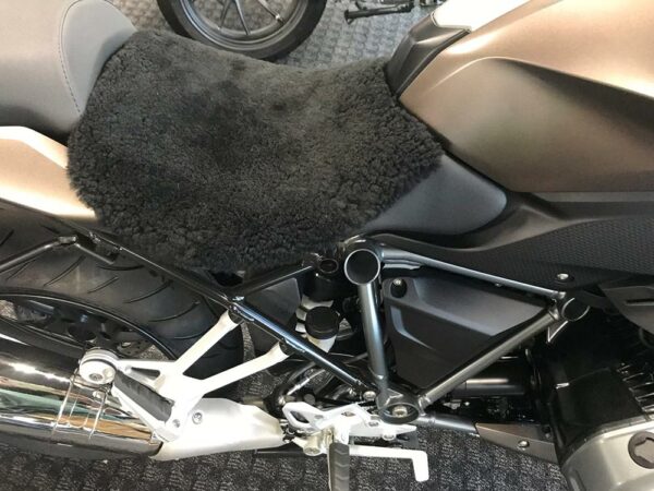 Close-up of a motorcycle seat covered with a black sheepskin seat cover