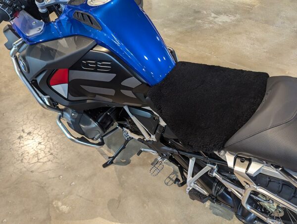A close-up view of a blue motorcycle with a black fleece seat cover